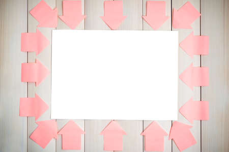 Stickers in form of arrows on the wooden background pointing at a white sheet.White sheet.Sticker arrows.Background of boards.の写真素材