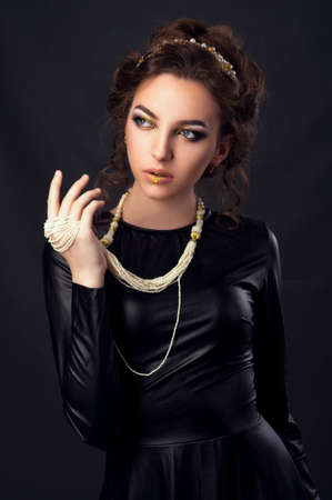 Beautiful young woman. Young girl. Girl in leather clothes. Portrait on a dark background. Beauty...