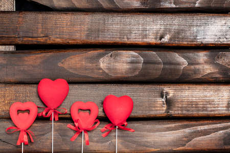 Four red hearts on sticks on a background of a dark wood.Hearts on sticks.Space for text.Valentine's...