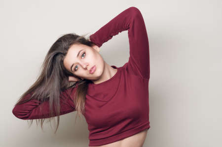 Beautiful young woman. Young girl. Girl in a red top and jeans boyfriends. Beauty portrait.  Girl portrait on a gray background. Toned imageの写真素材