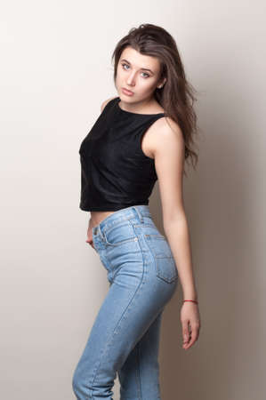 Beautiful young woman. Young girl. Girl in red knitted dress. Beauty portrait.  Girl portrait on a gray background. Toned imageの写真素材