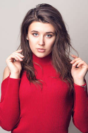 Beautiful young woman. Young girl. Girl in red knitted dress. Beauty portrait.  Girl portrait on a gray background. Toned imageの写真素材