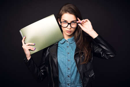 Beautiful young woman. Girl in blue overalls, wearing glasses and a leather jacket. Woman with...