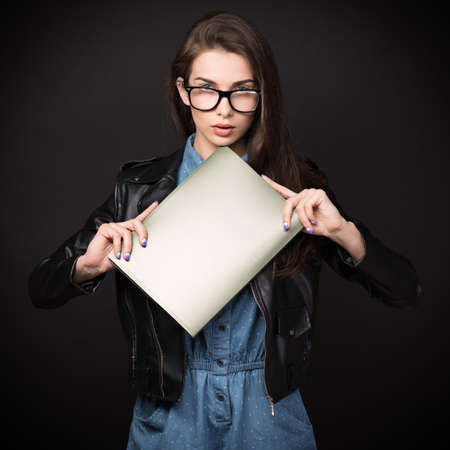 Beautiful young woman. Girl in blue overalls, wearing glasses and a leather jacket. Woman with folders. Sexy girl. High resolution photo. Hd images. Big size.の写真素材