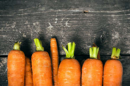Carrot on the old dark wooden boards. Bright carrots. Toned image. Selective focus.の写真素材