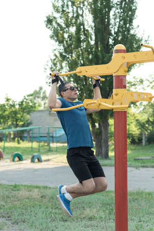 Handsome muscular man training in the city park at summer. Strong young athlete. Strong man. Athlete...
