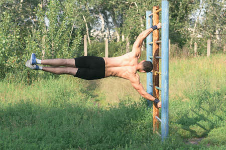 Strong young athlete. Strong young athlete is engaged in on an abandoned sports field. Exercises on...