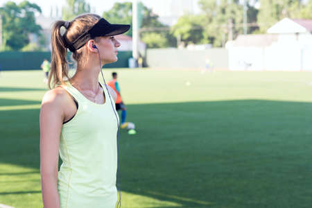 Sporty girl on the stadium. Football stadium. Slim sporty fitness woman. Bottle Shaker protein. Social media and fitness concept. Toned image.の写真素材