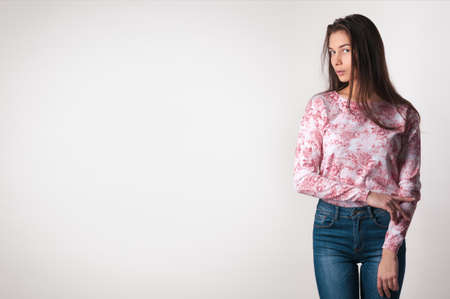 Beautiful young woman. Girl in casual clothes on a light background. Girl in jeans. Sexy girl. Space for text. Toned imageの写真素材