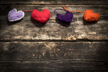 Valentine's Day. Colorful knitted hearts. Red heart on the dark old boards. Valentines day. Heart pendant. Red heart. Valentine cards. Space for text. Eighth of March. International Women's Day.の写真素材
