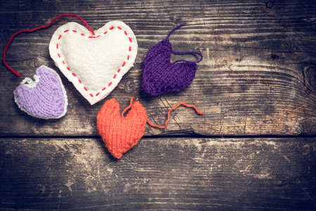 Colorful knitted hearts on the dark old boardsの写真素材