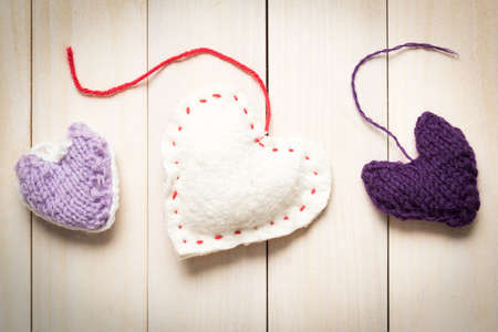 Colorful knitted hearts on light, wooden boardsの写真素材