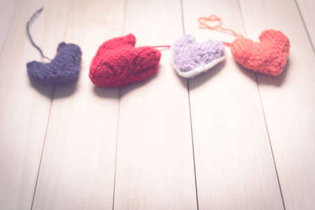 Colorful knitted hearts on light, wooden boardsの写真素材