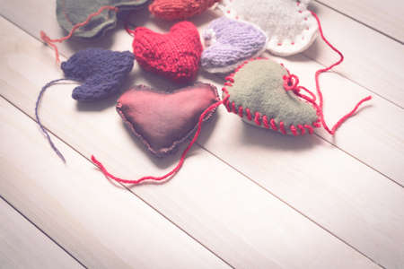 Colorful knitted hearts on light, wooden boardsの写真素材