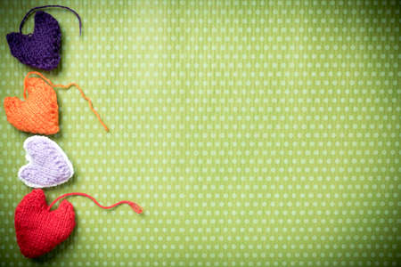 Valentines Day. Colorful knitted hearts on a vintage background in polka dots. Red heart. Green background. Valentine's day. Heart pendant. Valentine cards. Eighth of March. International Women's Day.の写真素材