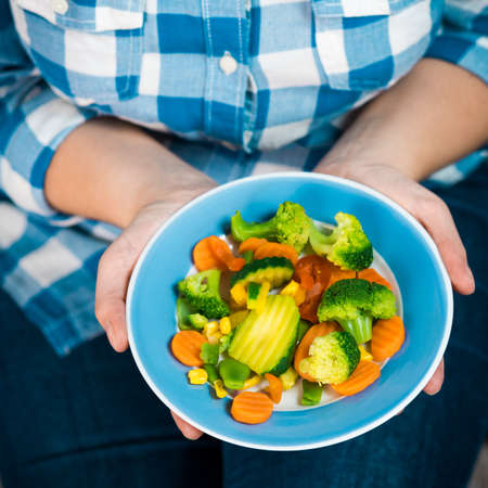 Girl with a plate of vegetables in hands