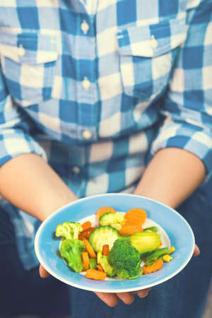 The girl holds a plate with vegetablesの写真素材