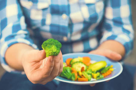 The girl holds a plate with vegetablesの写真素材