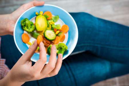 Girl with a plate of vegetables in handsの写真素材