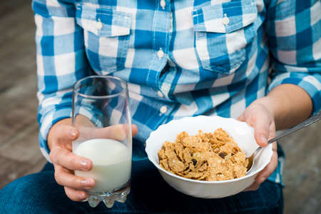 Girl with a plate of cereal. Flakes from whole wheat with dried fruits. Healthy eating concept. A...