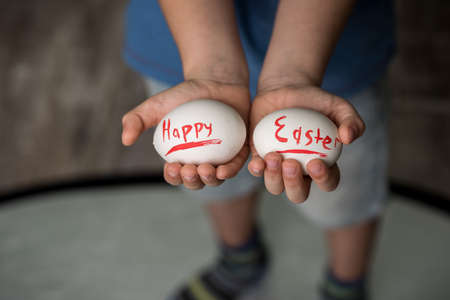 Eggs with the inscription Happy Easter in the hands of a child. Green background. Easter ideas....