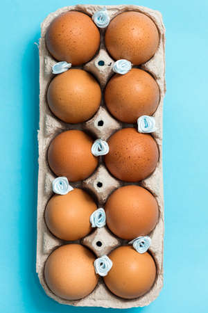 Brown Easter eggs in an eco carton pack lie on a beautiful blue background. Easter ideas. Space for...