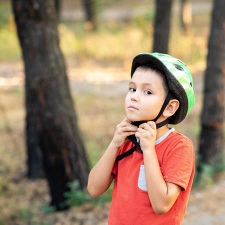 A boy puts a green helmet on his head.の写真素材