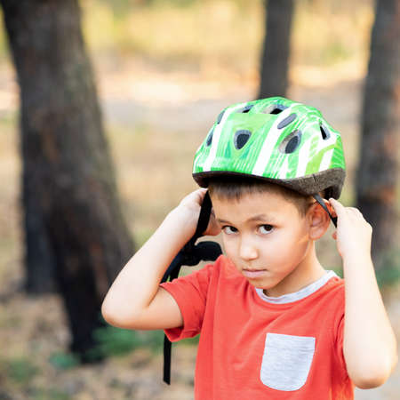 A boy puts a green helmet on his head.の写真素材