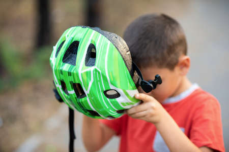 A boy puts a green helmet on his head.の写真素材
