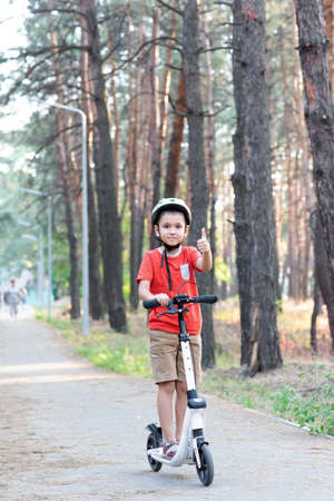 A boy rides a scooter in the forest.