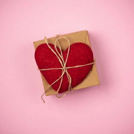 Red heart with a gift to Valentine's Day on a beautiful pink background. Heart pendant. Space for...