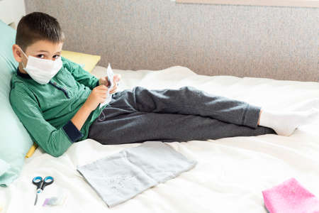 Stay at home quarantine coronavirus pandemic prevention. The child in the mask is engaged in beadwork from boredom. Prevention epidemic. COVID-19.の写真素材