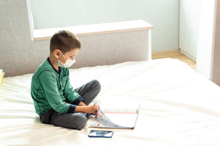 Stay at home quarantine coronavirus pandemic prevention. A masked child learns lessons during the...