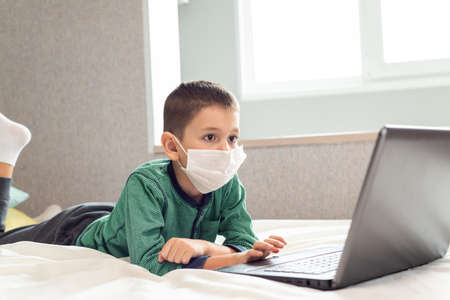 Stay at home quarantine coronavirus pandemic prevention. A child learns online on a laptop during...