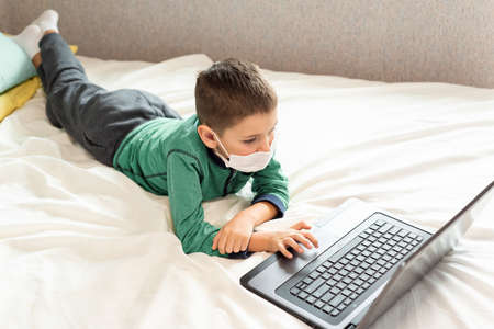 Stay at home quarantine coronavirus pandemic prevention. A child learns online on a laptop during...