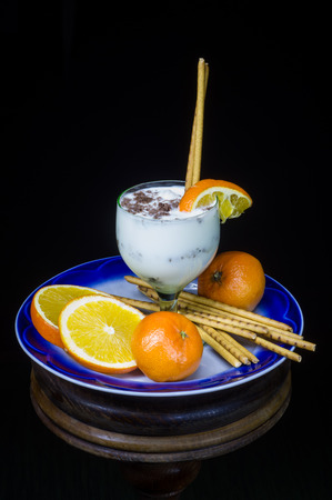 Milky dessert with fruit and grated chocolate on a plate in a glassの写真素材