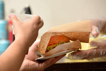 cook gives a grilled beef burger to a guest at street food festivalの写真素材
