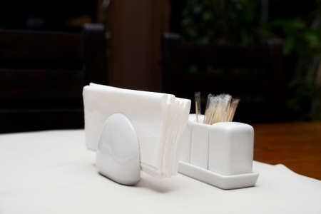 Paper napkins in the holder with salt pepper and toothpicks on table in restaurantの写真素材