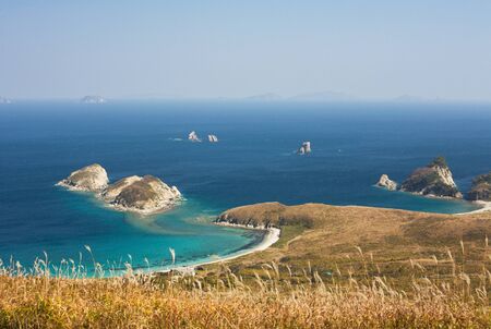 waterscape, emerald forest and marine blue combines the thin strip of beachの写真素材