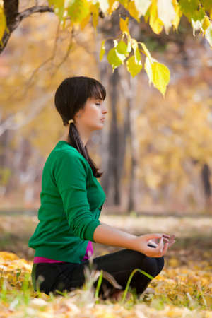 beautiful girl with dark hair, yoga in the yellow autumn leavesの写真素材