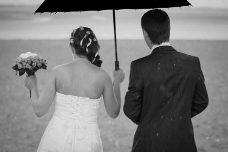 couple walking in the rain on the beachの写真素材