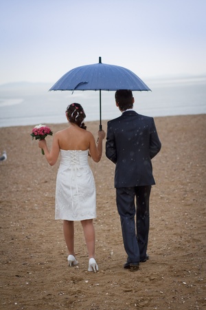 couple walking in the rain on the beachの写真素材