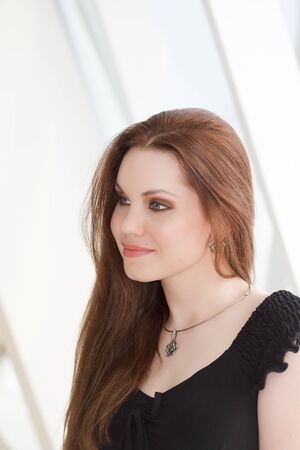 portrait fashion girl with red hair sitting in a white studioの写真素材