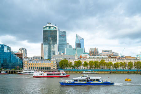 London - October 2019: view of the skyscrapers of City of London from the south bank of the Thames. Ships are floating on the river.のeditorial素材