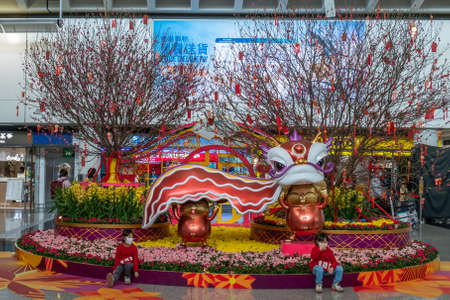 Hong Kong, China - 2020: children in medical masks at Hong Kong International Airport. Two Chinese twin girls are sitting on the edge of a flower bed with mouses statues. People in the distance.のeditorial素材