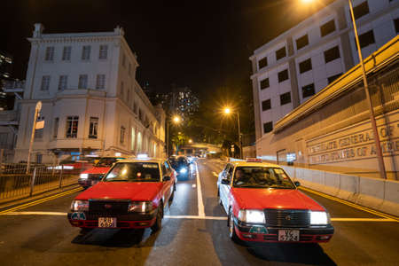 Hong Kong, China - 2020: taxi in Hong Kong on the street at night. Red and white Toyota cars.のeditorial素材