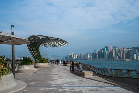 Hong Kong - 2020: Avenue of Stars, view of Victoria Harbor. Original flower beds and benches. People walk on the promenade.のeditorial素材