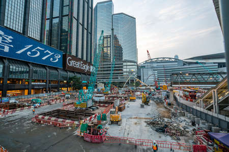 Hong Kong - 2020: construction near the Hong Kong Convention And Exhibition Center. Cranes, special equipment, workers in overalls and helmets, fences.のeditorial素材