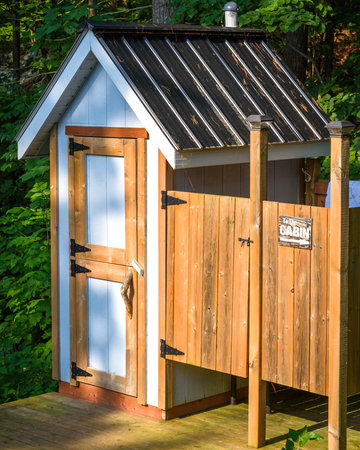 A small outdoor toilet in the woods on a sunny summer day.の写真素材