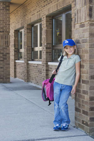 Eight year old girl waiting outside schoolの写真素材